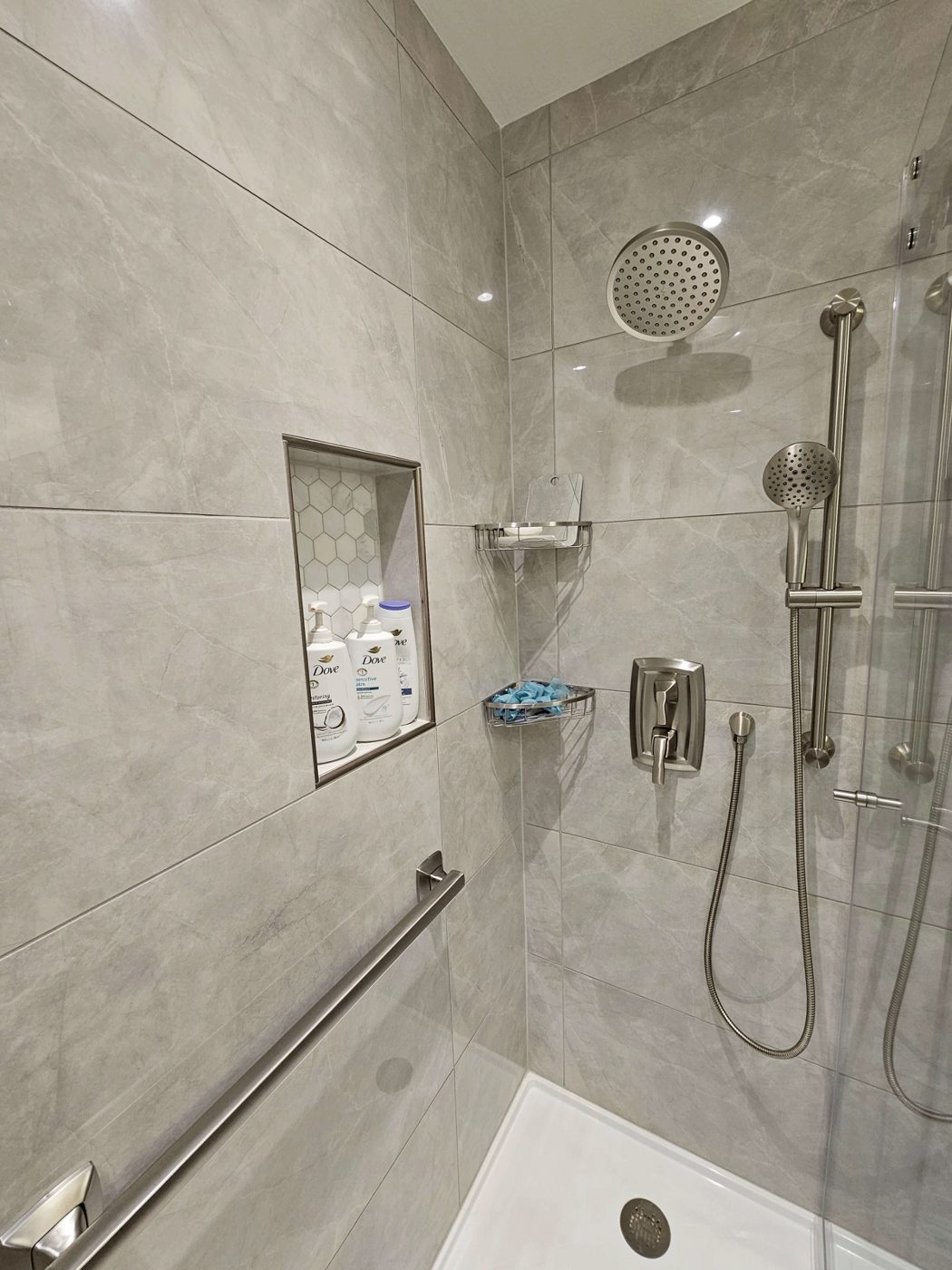 Gray tile walk-in shower with a rainfall head and recessed shelving