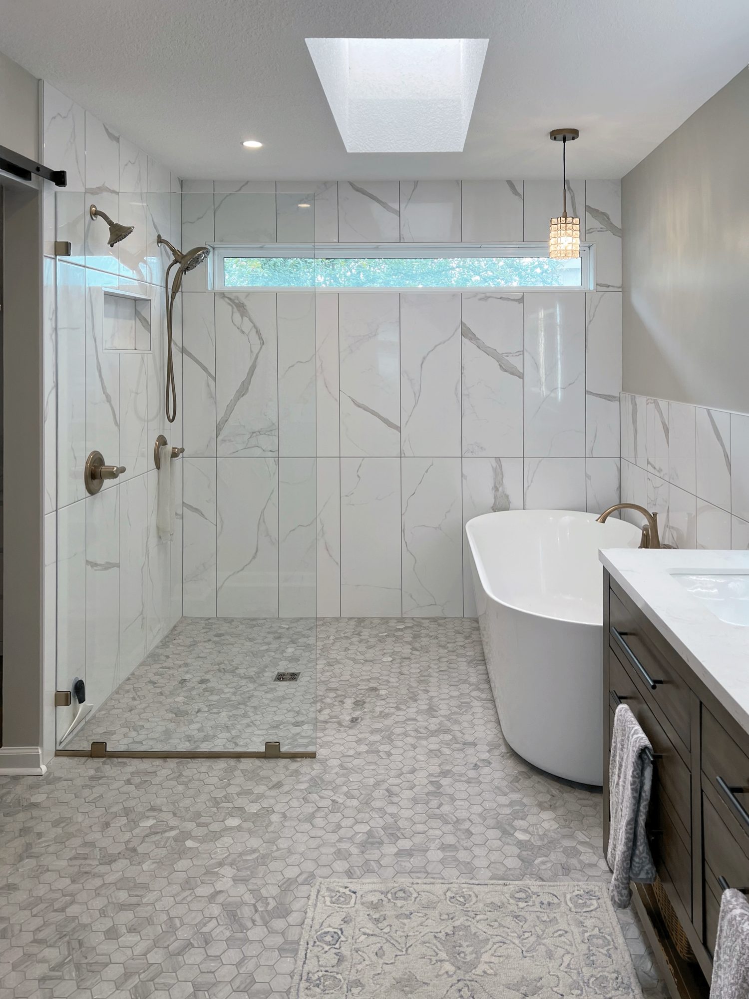 A finished Bath Pro KC bathroom with a freestanding tub, walk-in tile shower, and a skylight